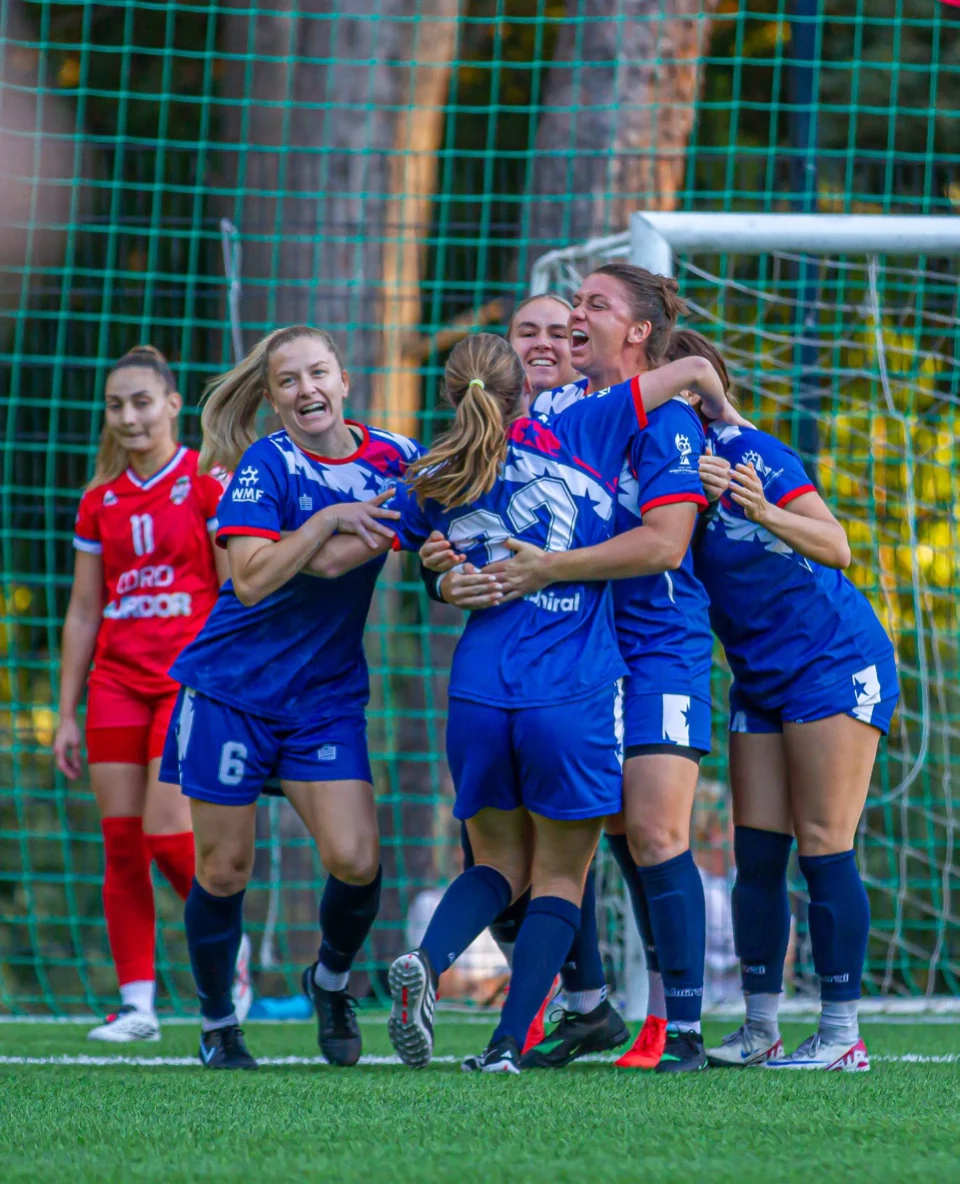 Mini Football USA players celebrate a goal in the navy home kit